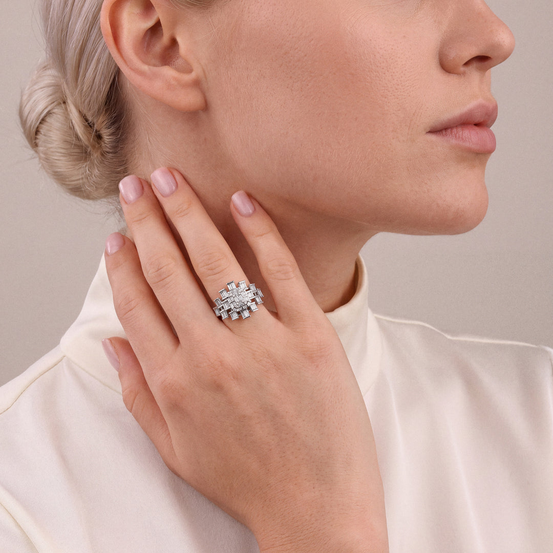 1.06 ct natural diamond baguette cocktail ring in 14K white gold worn on the ring finger, fingertips at the side of the neck, ivory satin high-neck top