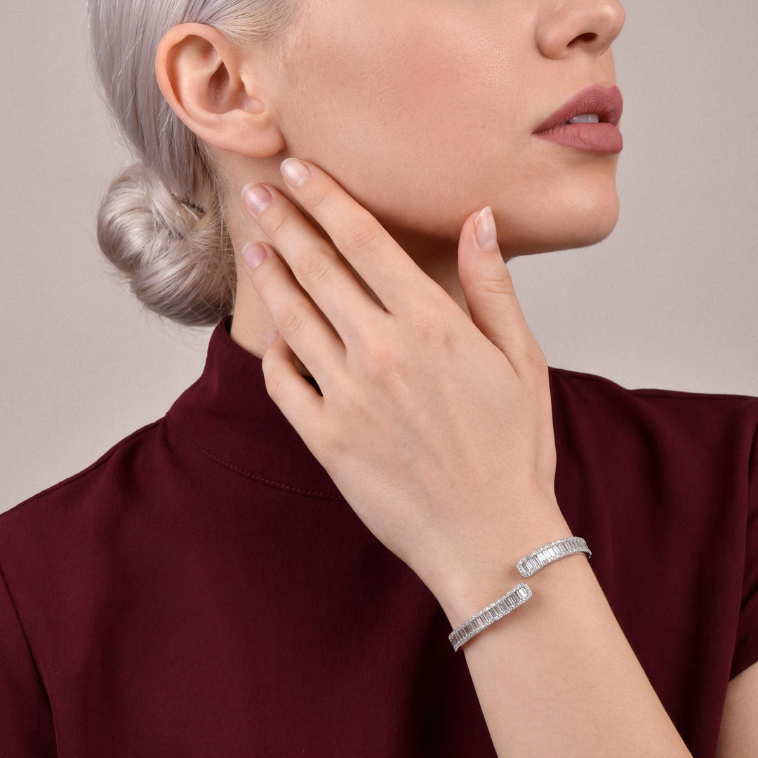 Woman in an oxblood mock-neck top wearing a 3.46 ct natural diamond baguette bypass cuff in 18K white gold