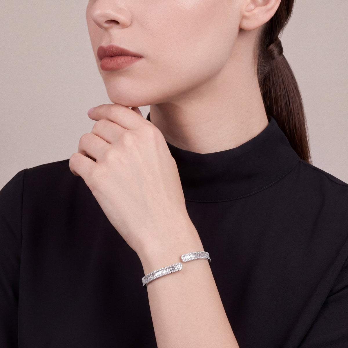 Woman in a black mock-neck top wearing a natural diamond baguette and round diamond bypass cuff in 18K white gold