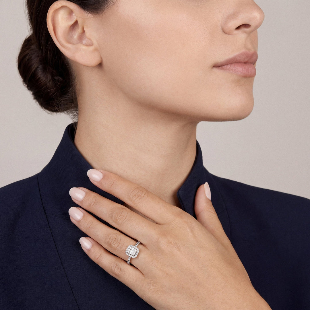 Woman in a navy stand-collar jacket wearing a 0.43 ct tw natural diamond baguette illusion halo ring in 14K white gold on the ring finger, fingertips at the collar