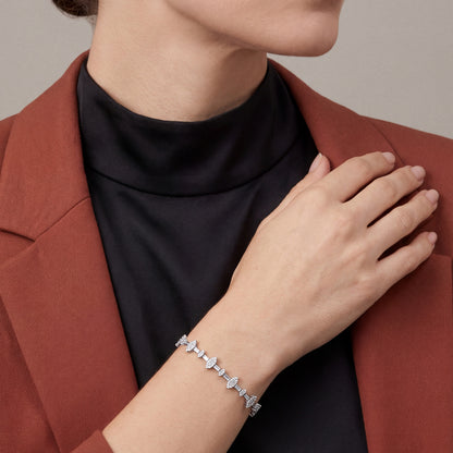 Woman in a rust blazer over a black mock neck wearing a natural diamond baguette marquise cluster bracelet in 14K white gold