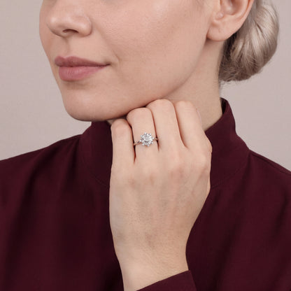 Woman in an oxblood silk-crepe high-collar blouse wearing a baguette natural diamond snowflake ring in 14K white gold, fist under her chin