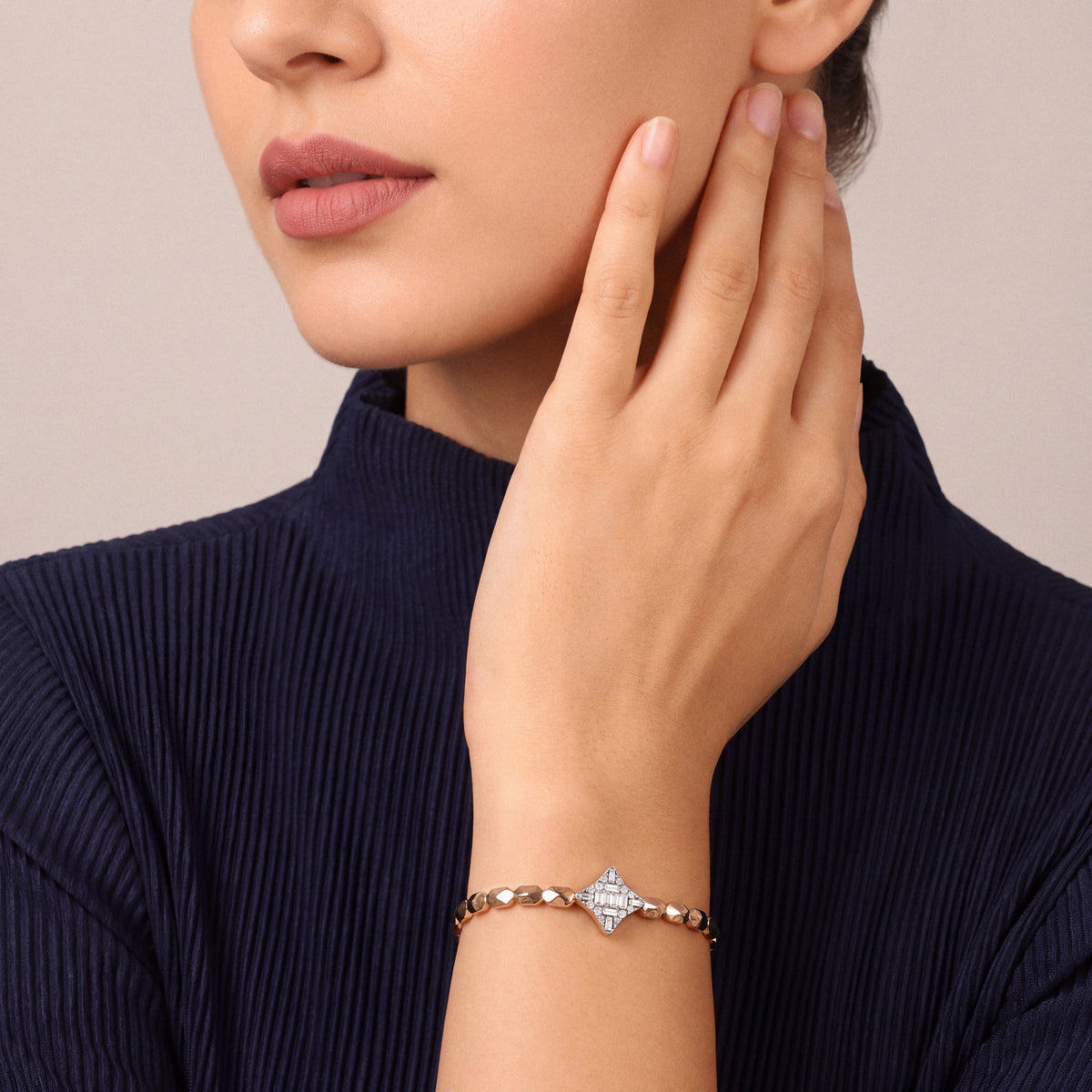 Woman in a navy pleated top wearing a natural diamond baguette star bracelet in 14K rose and white gold