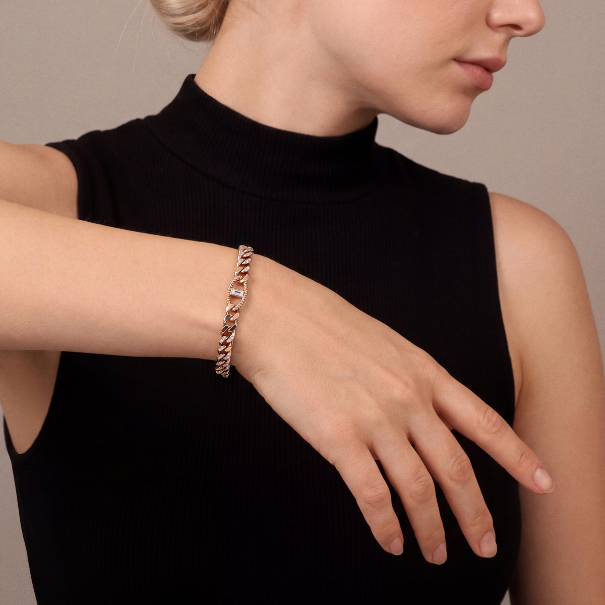 Woman in a black sleeveless mock-neck top wearing a natural diamond baguette station curb chain bracelet in 14K rose gold