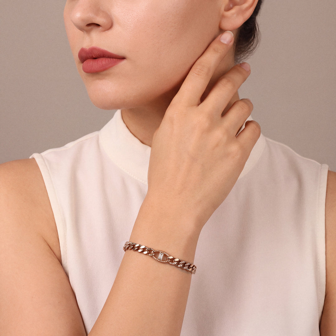 Woman in an ivory silk stand-collar top wearing a natural diamond baguette curb chain bracelet in 14K rose gold