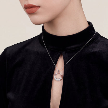 Woman in a black velvet mock-neck top wearing the natural diamond double circle pendant necklace in 14K white gold