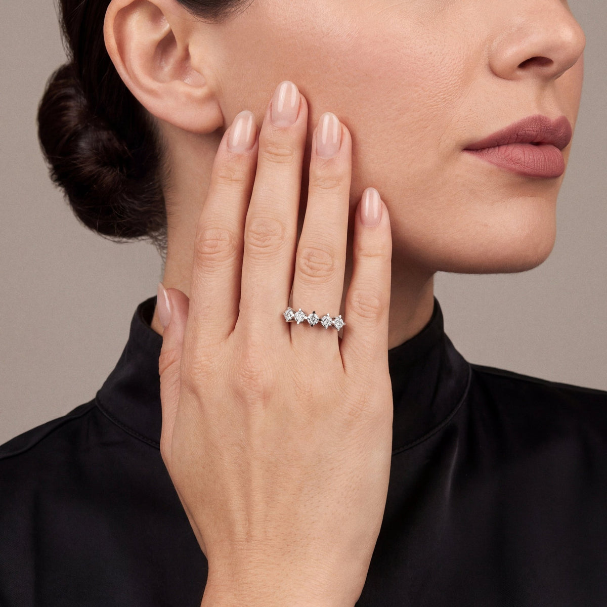Natural diamond five-stone crown ring in 14K white gold worn on the ring finger, palm resting on the cheek, black silk high-neck top