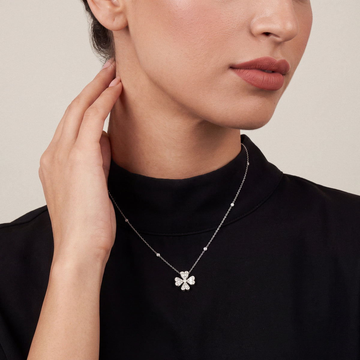 Woman in a black mock-neck top wearing the natural diamond heart clover pendant necklace in 18K white gold