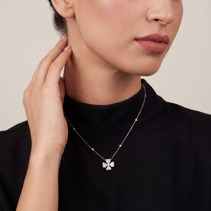 Woman in a black mock-neck top wearing the natural diamond heart clover pendant necklace in 18K white gold