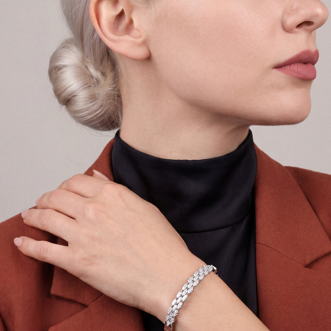 Woman in a rust blazer wearing a natural diamond marquise bangle in 18K white gold, hand at the opposite lapel
