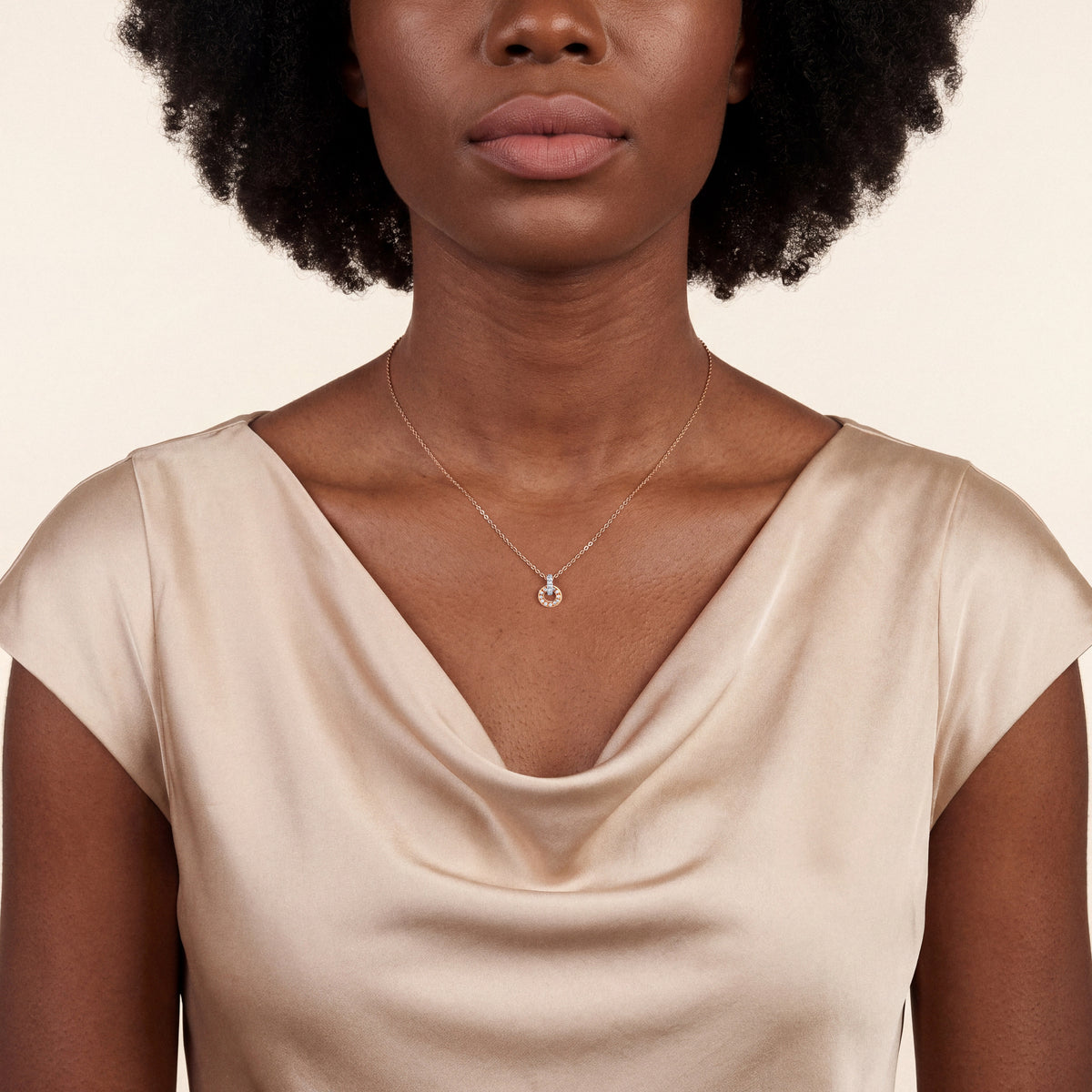Woman in a champagne satin cowl-neck top wearing the natural diamond open circle pendant necklace in 18K rose gold