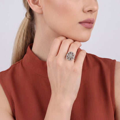 Woman in a rust stand-collar top wearing a natural diamond oval halo cocktail ring in 14K white gold, hand curled under the chin