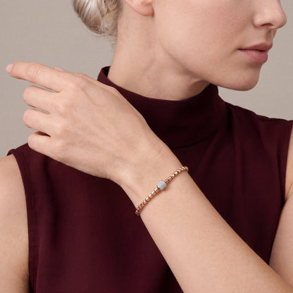 Woman in an oxblood sleeveless high mock-neck top wearing the natural diamond pavé barrel bead bracelet in 14K rose and white gold