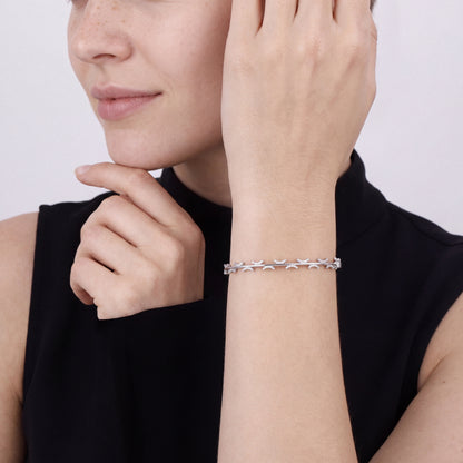 Woman in a black sleeveless mock-neck top wearing a natural diamond pavé crescent bangle bracelet in 14K white gold