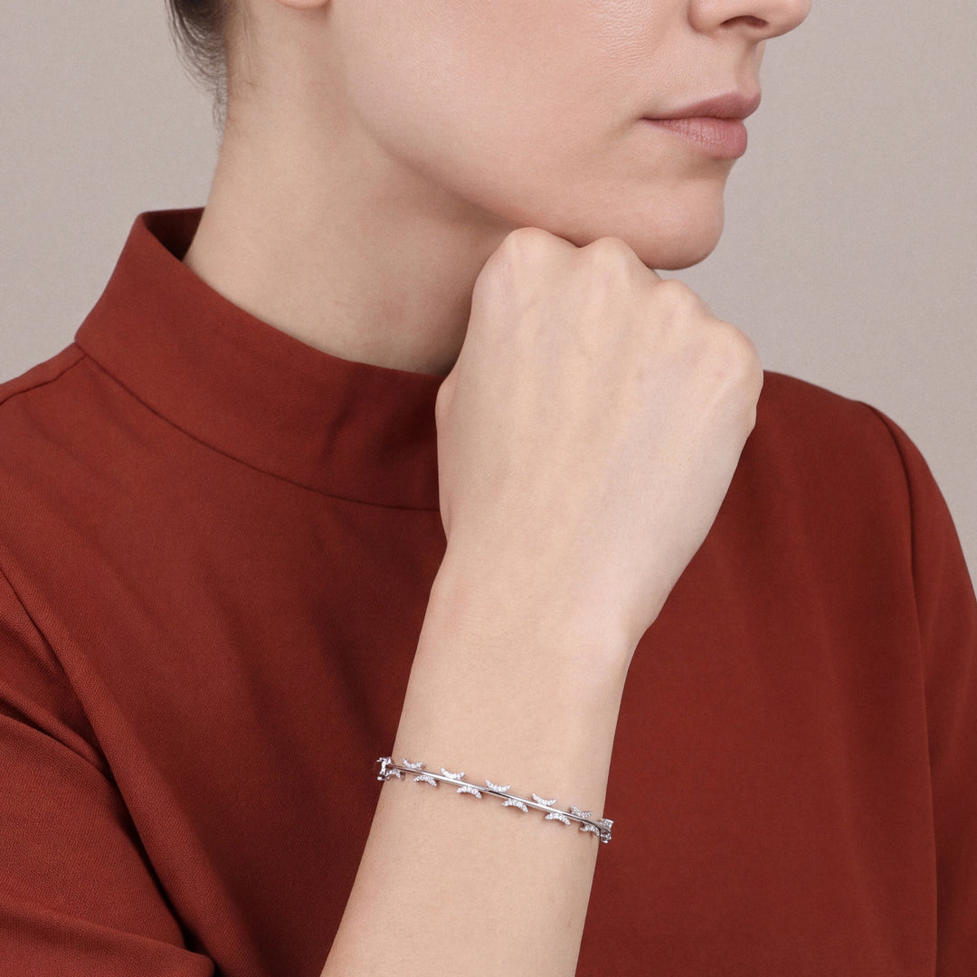 Woman in a rust stand-collar top wearing a natural diamond pavé crescent bangle bracelet in 14K white gold
