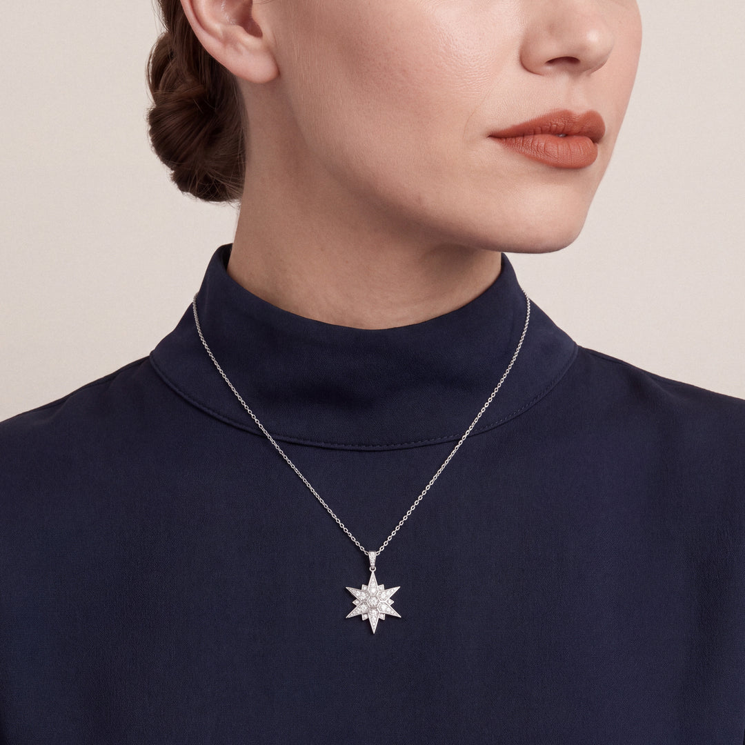 Woman in a navy funnel-neck top wearing the natural diamond pavé starburst pendant necklace in 14K white gold