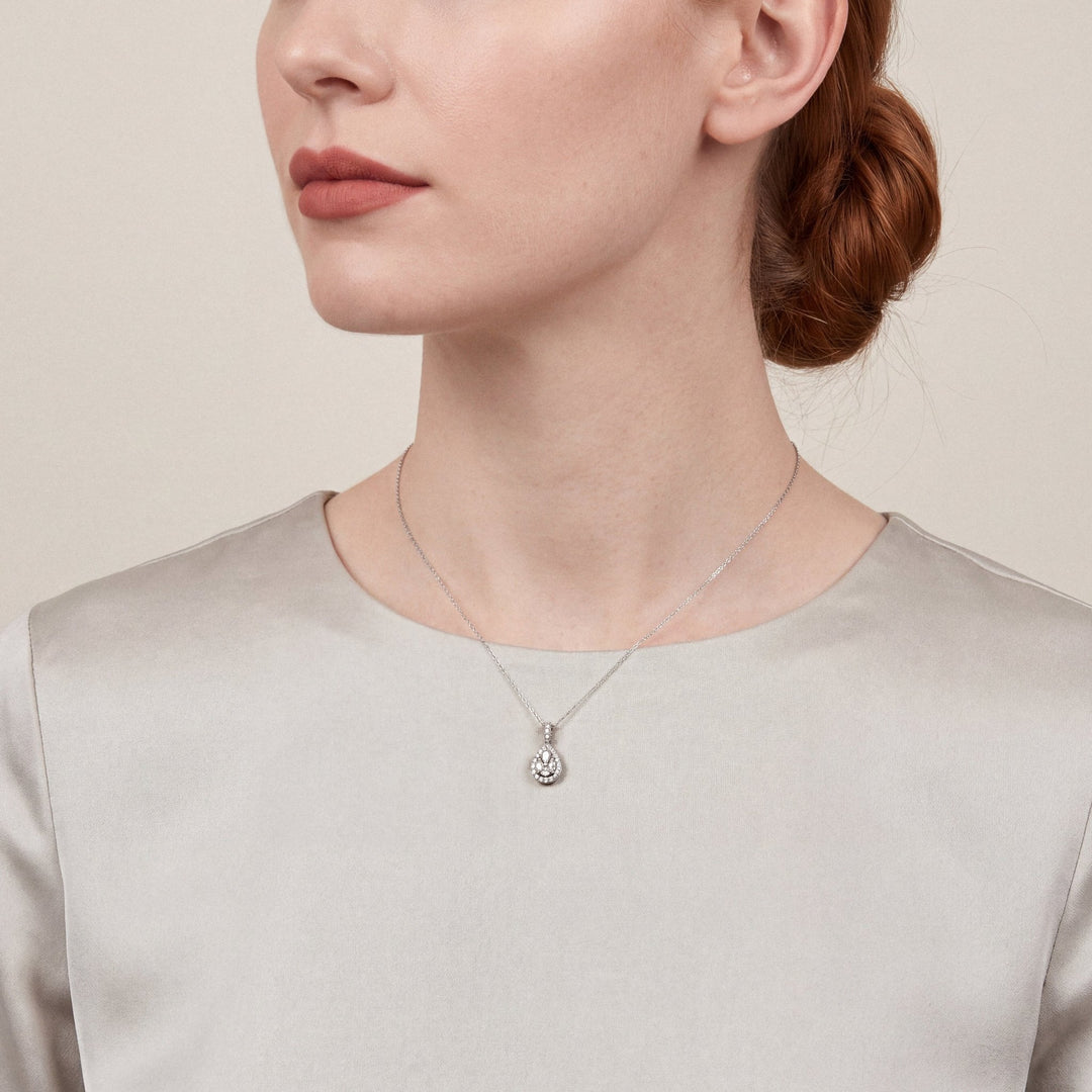 Model in an oyster satin high-neck top wearing a 0.51 ct natural diamond pear halo pendant necklace in 14K white gold