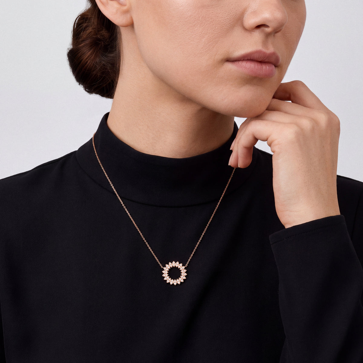 Woman in a black silk-crepe mock-neck top wearing a 0.44 ct natural diamond petal circle pendant necklace in 14K rose gold.