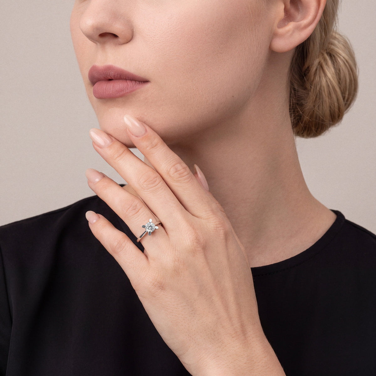 Woman in a black silk crepe top wearing a 0.60 ct natural round diamond solitaire ring in 14K white gold on the ring finger, fingertips at the chin