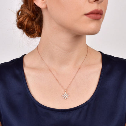 Woman in a navy satin top wearing the natural diamond starburst pendant necklace in 14K rose gold