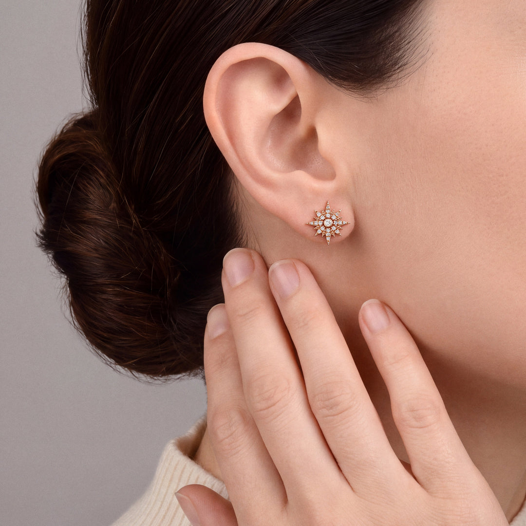Woman in an ivory cashmere mock neck wearing a natural diamond starburst stud earring in 14K rose gold