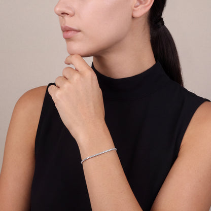Woman in a black sleeveless high-neck top wearing a natural diamond tennis bracelet in 14K white gold, hand at the chin