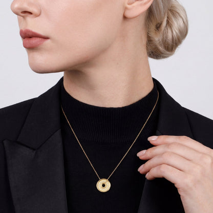 Woman in a black tuxedo jacket over a black mock neck wearing a 0.16 ct tw natural diamond coin disc pendant necklace in 18K yellow gold