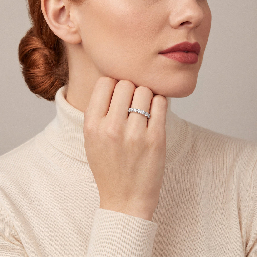 Model in a cream cashmere turtleneck wearing a 1.00 ct tw natural diamond three-quarter eternity ring in 14K white gold, hand under her chin
