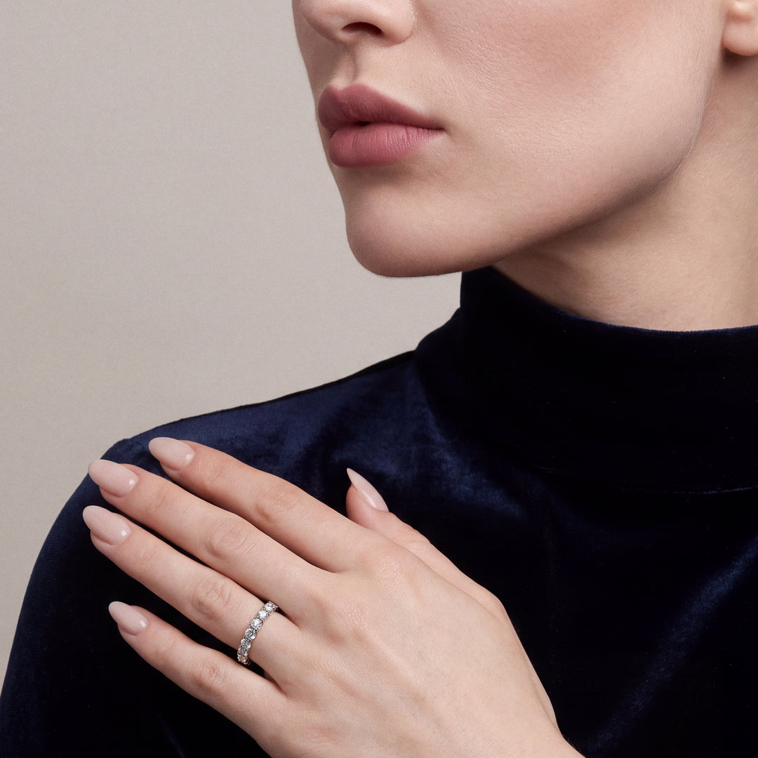 Model in a navy velvet funnel-neck top wearing a natural diamond three-quarter eternity ring in 14K white gold, hand on her shoulder