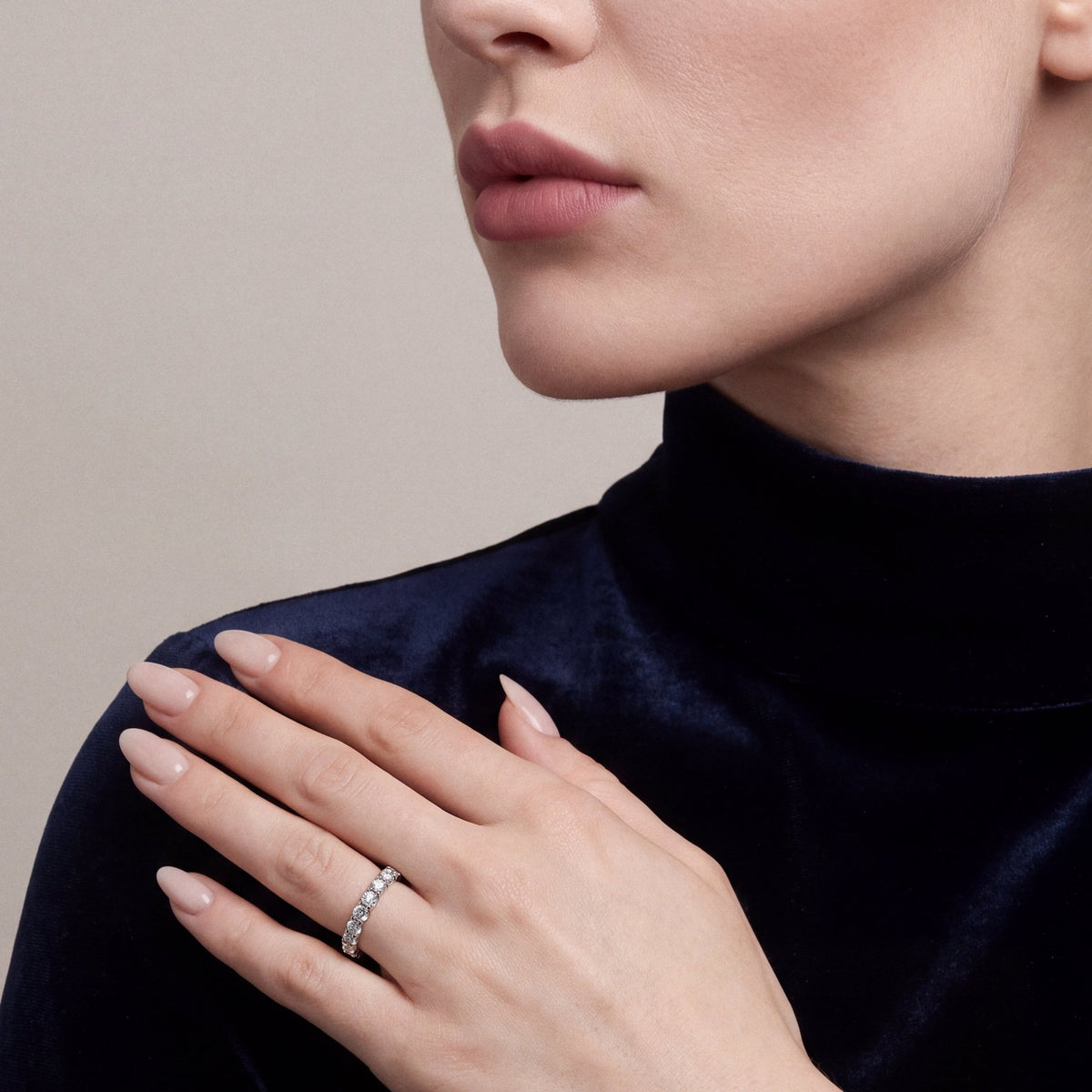 Model in a navy velvet funnel-neck top wearing a natural diamond three-quarter eternity ring in 14K white gold, hand on her shoulder