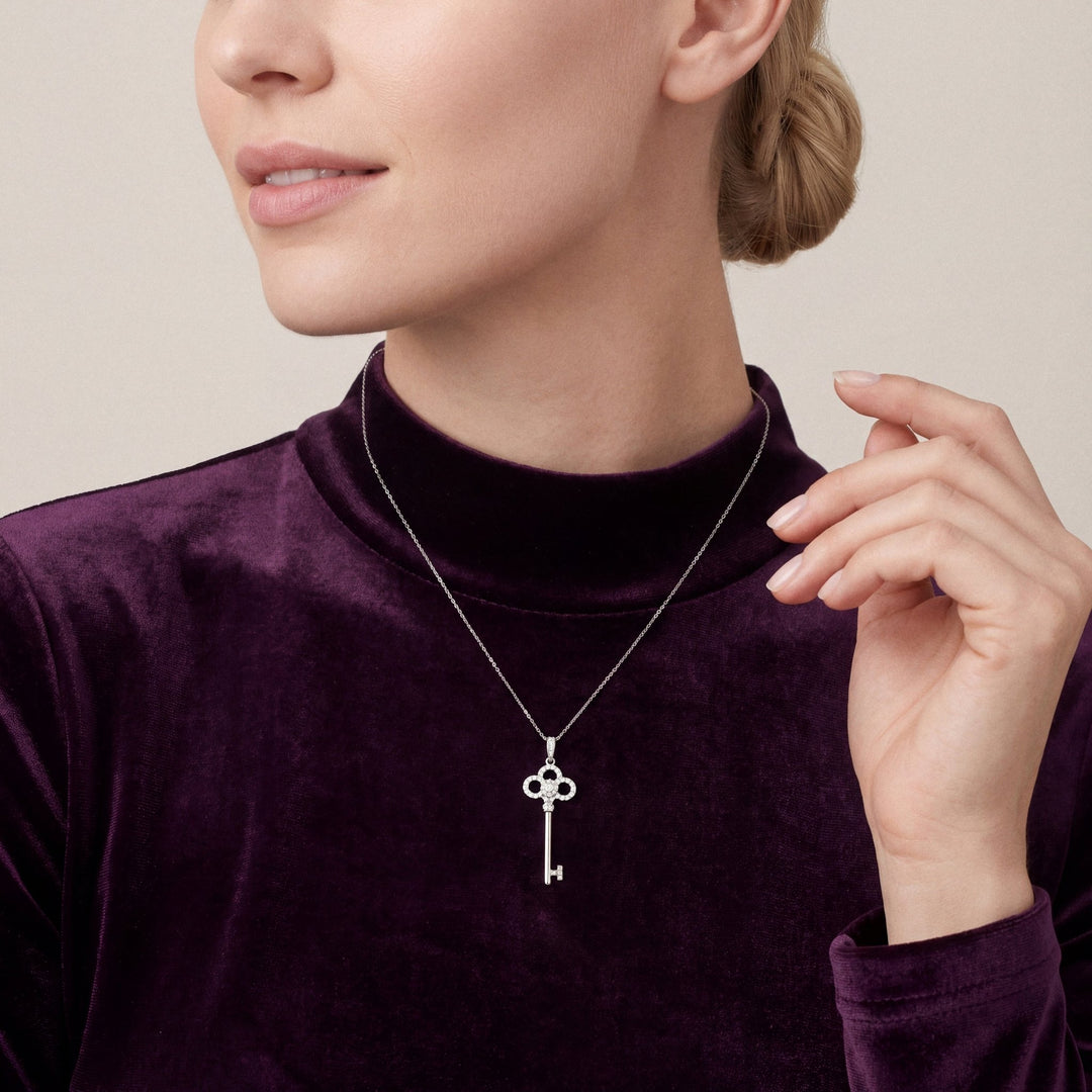 Woman in a plum velvet mock-neck top wearing a natural diamond trefoil key pendant necklace in 14K white gold