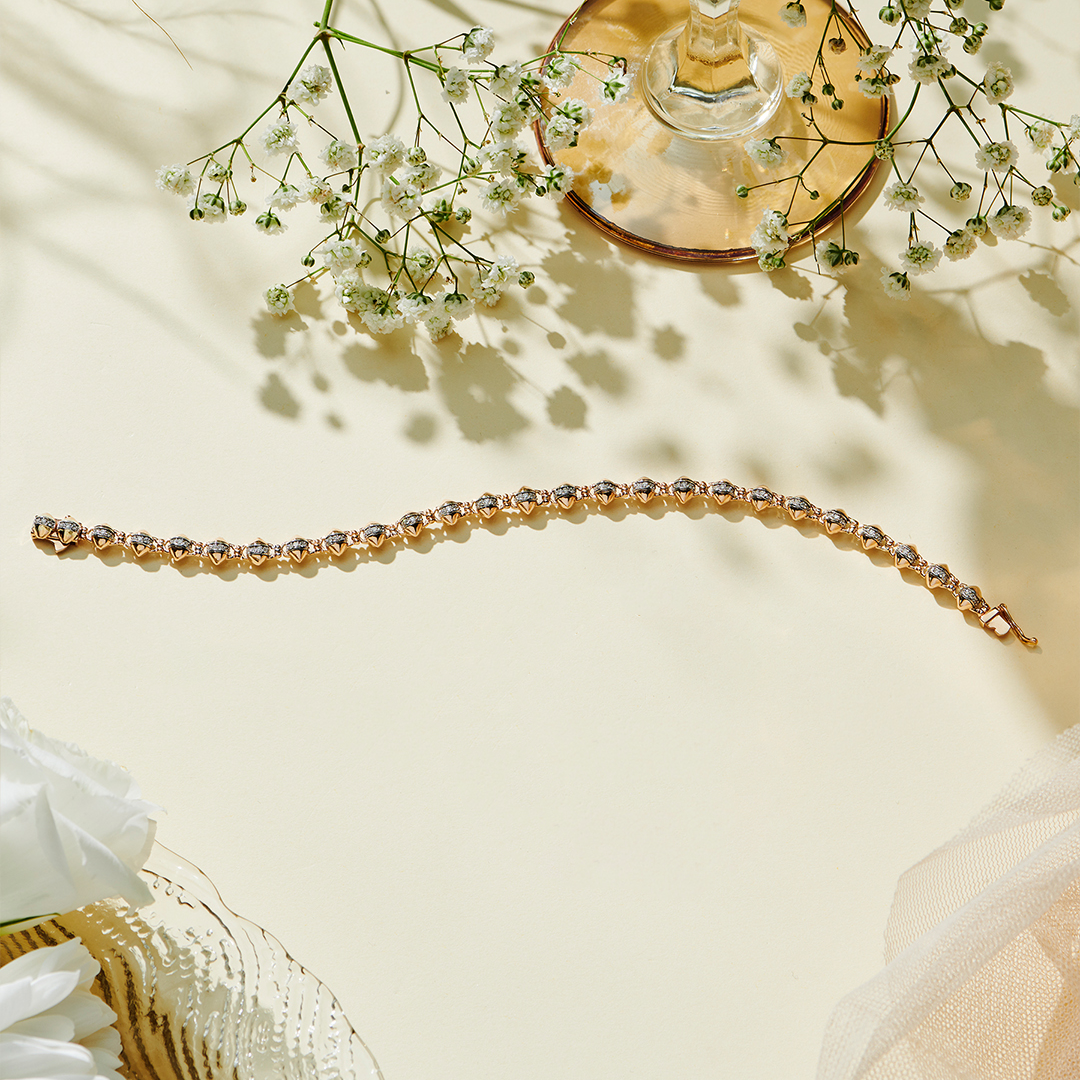 Natural diamond two-tone link bracelet in 14K rose gold laid on cream linen with flowers
