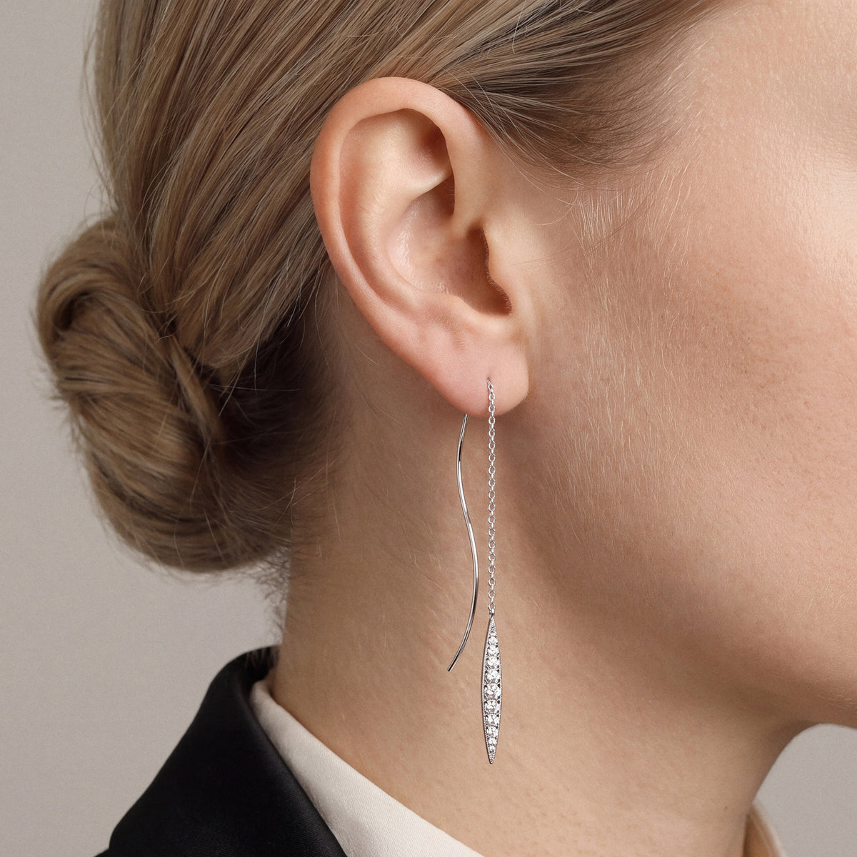 Model in a black tuxedo jacket and ivory high neck wearing a navette natural diamond threader earring in 14K white gold