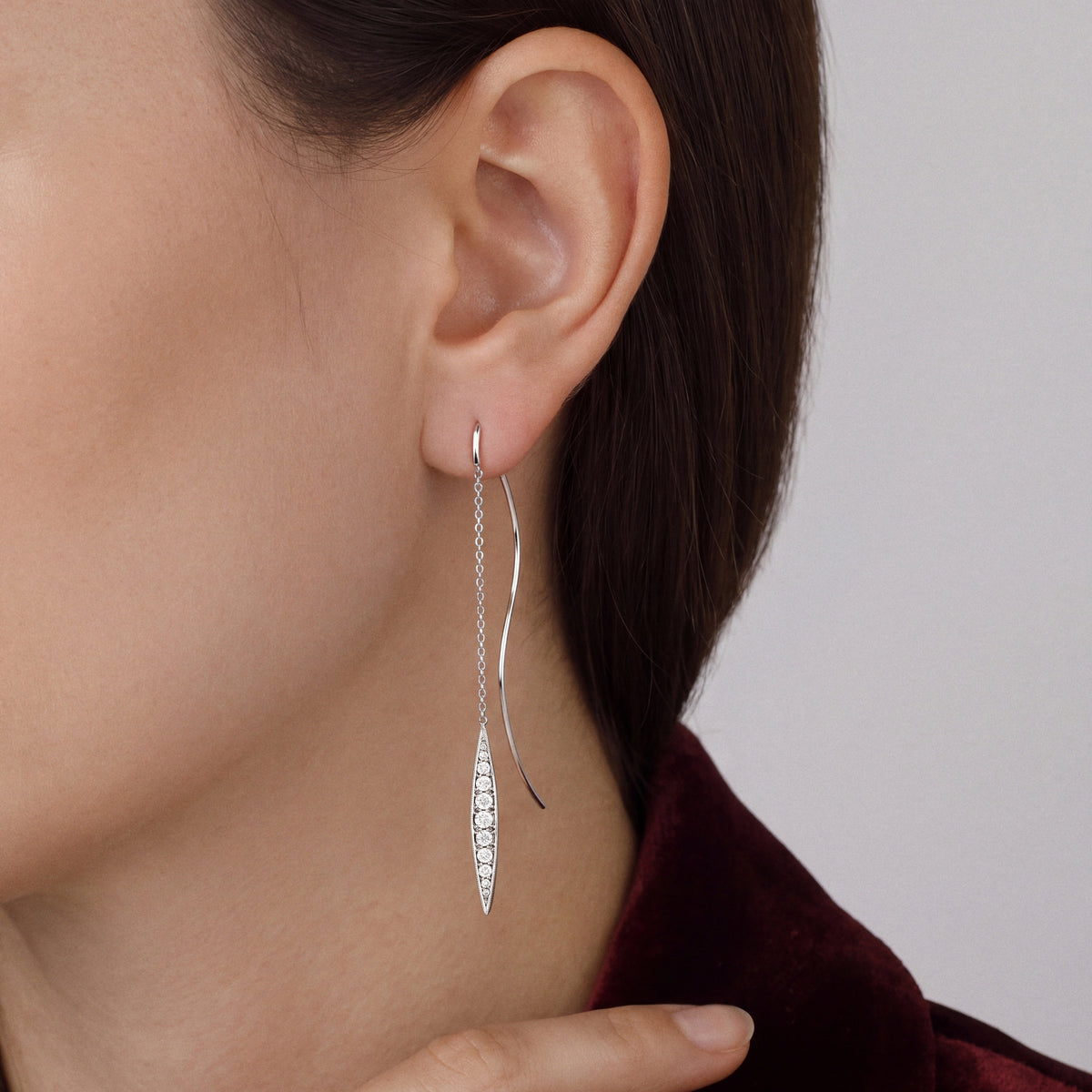Model in an oxblood velvet jacket in profile wearing a navette natural diamond threader earring in 14K white gold