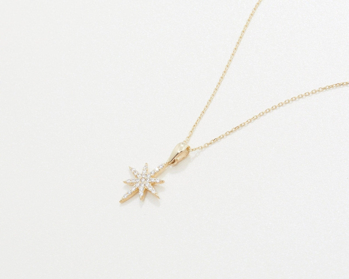 The North Star Necklace in 14K solid gold laid flat, showing the star and its bail.