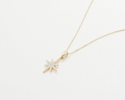 The North Star Necklace in 14K solid gold laid flat, showing the star and its bail.