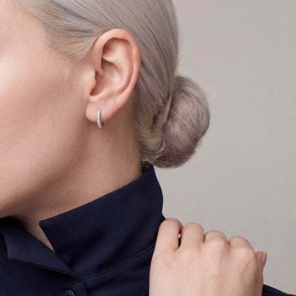 Pavé natural diamond huggie hoop earring in 14K white gold, worn with a midnight-navy silk shirt collar