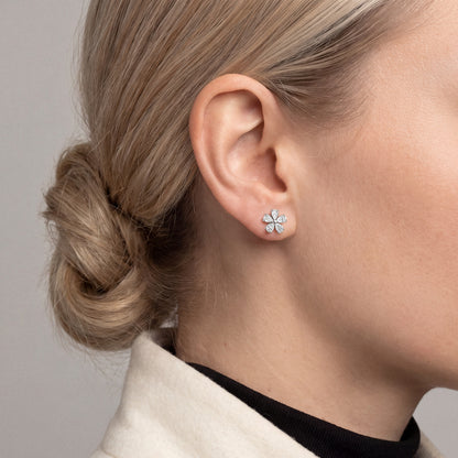 Woman in an ivory wool jacket wearing a pear-cut natural diamond flower stud earring in 14K white gold, side profile