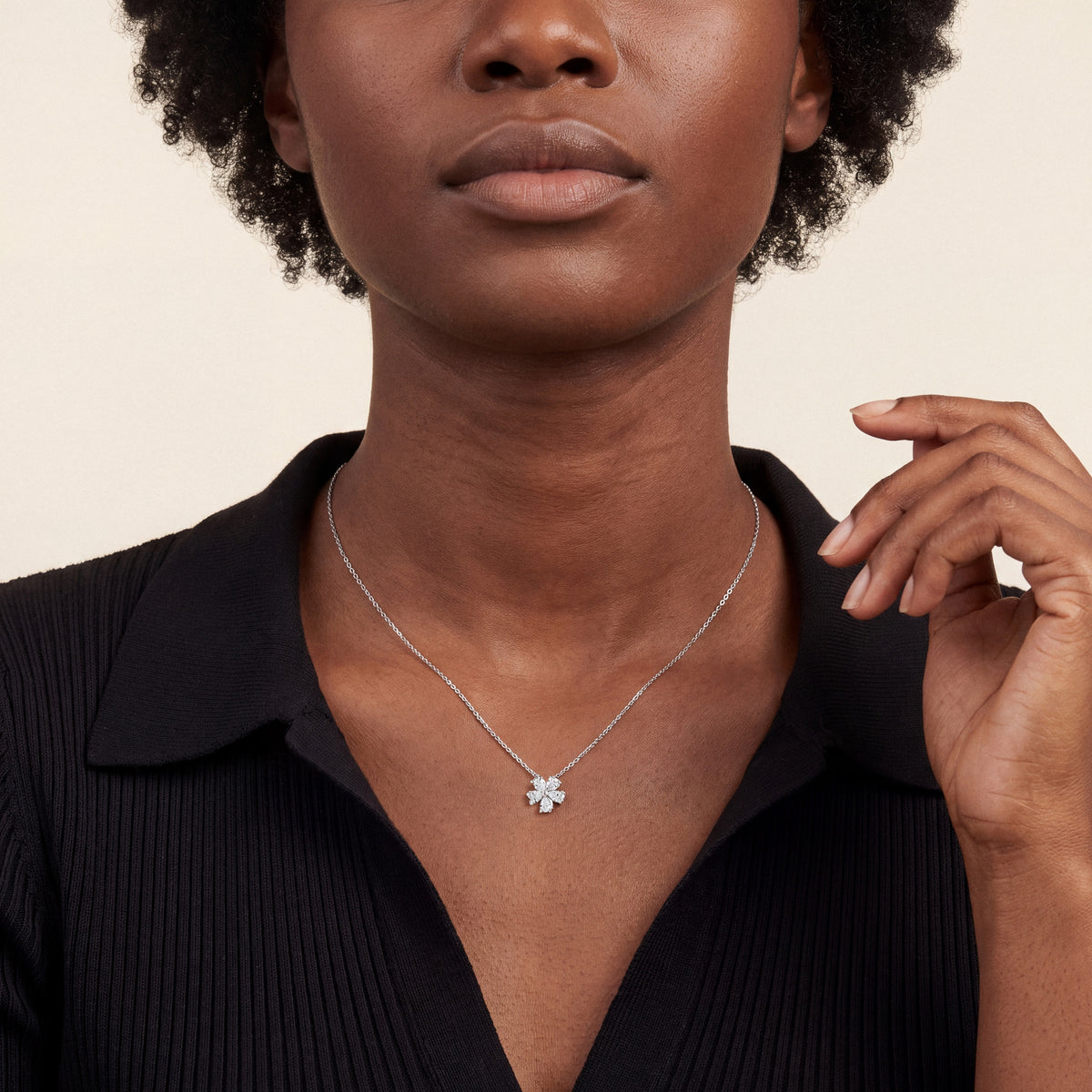 Woman in a black knit polo wearing the pear-cut natural diamond flower pendant necklace in 14K white gold