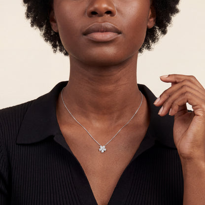 Woman in a black knit polo wearing the pear-cut natural diamond flower pendant necklace in 14K white gold