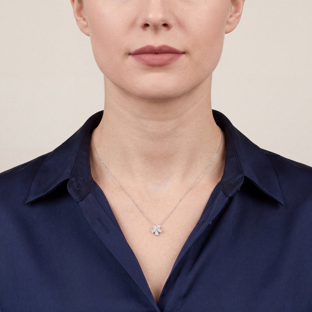 Woman in a navy silk shirt wearing the pear-cut natural diamond flower pendant necklace in 14K white gold