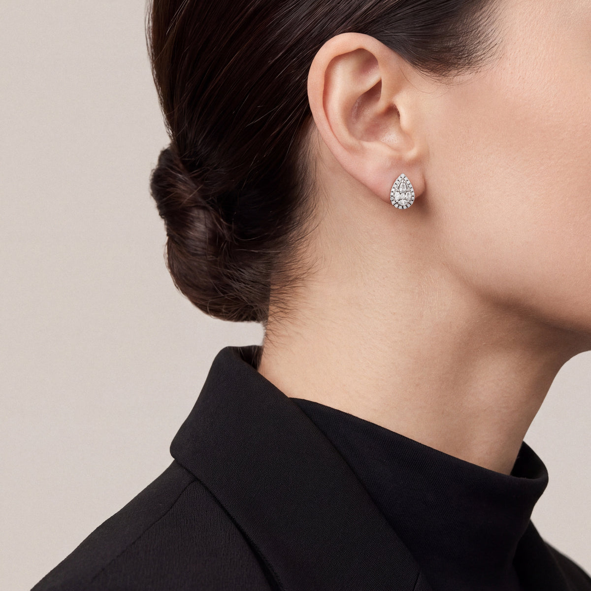 Woman in profile in a black blazer with a turned-up collar wearing a pear-shaped natural diamond cluster halo stud earring in 14K white gold