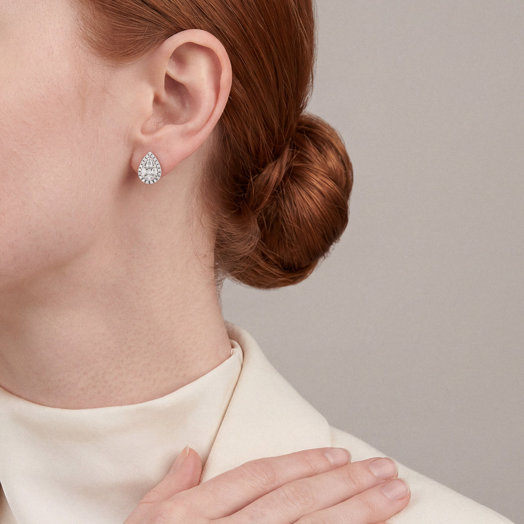 Woman in a cream wool blazer and high mock neck wearing a pear-shaped natural diamond cluster halo stud earring in 14K white gold