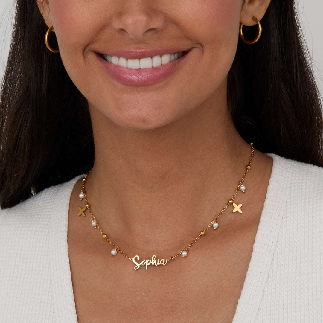 Pearl Name Necklace with Gold Petal Charms worn close-up — personalized gold script name with pearl drops.