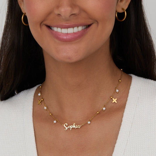 Pearl Name Necklace with Gold Petal Charms worn close-up — personalized gold script name with pearl drops.