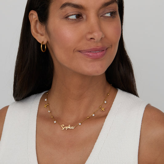 Woman wearing the Pearl Name Necklace with Gold Petal Charms in 18K gold-plated steel.