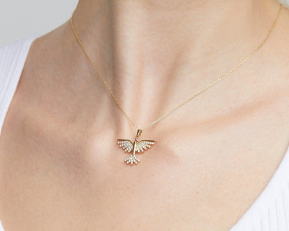 Close-up of the 14K solid gold phoenix pendant on skin, showing the CZ stones on the wings and tail.