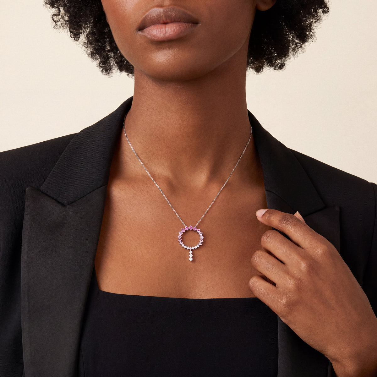 Woman in a black tuxedo jacket wearing the pink gemstone and natural diamond open circle drop necklace in 14K white gold