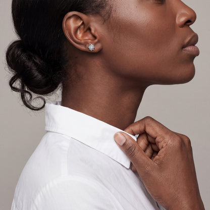Model in a white shirt wearing a 0.97 ctw princess-cut natural diamond solitaire stud earring in 14K white gold