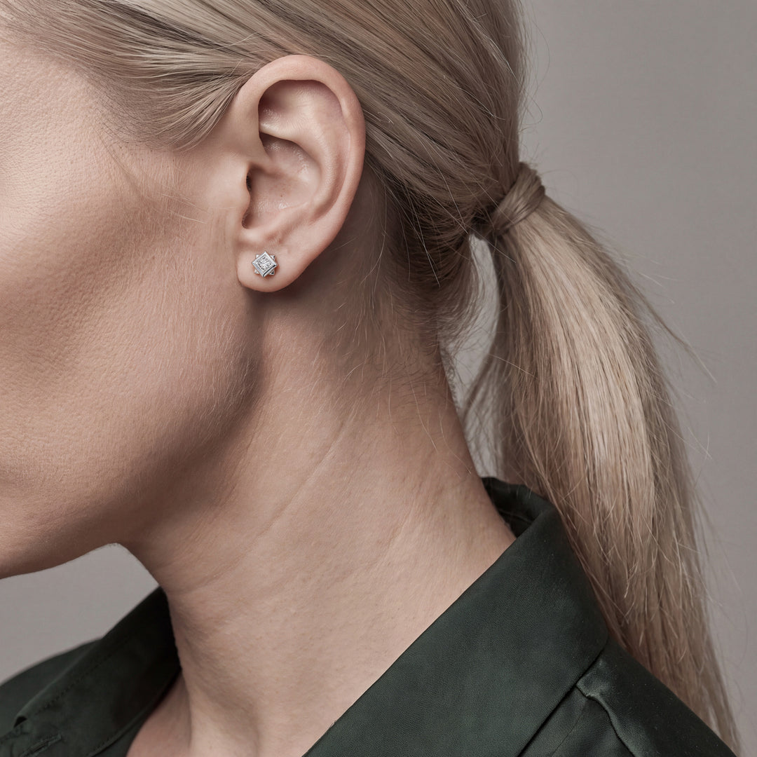 Profile view of a princess-cut natural diamond solitaire stud earring in 14K white gold worn on the ear